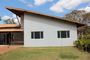 une maison blanche avec une cour d'herbe devant elle dans l'établissement Chacara Alto Padrão Recanto Felicidade Paraopeba, à Paraopeba