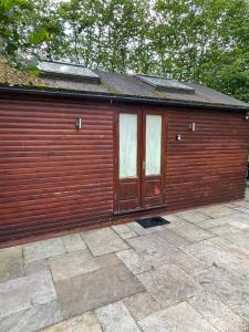 a large wooden building with two doors on it at The Snug - Luxury En-suite Cabin with Sauna in Grays Thurrock in Grays Thurrock
