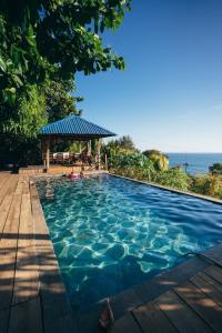 uma piscina com um gazebo junto ao oceano em El Xalli em El Zonte