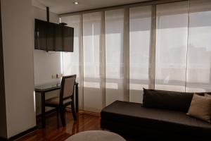 a living room with a couch and a desk and a television at One Sixteen Hotel in Bogotá