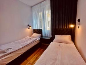 2 camas en una habitación pequeña con ventana en Apartament Wełniany z SAUNĄ en Toruń