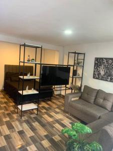 een woonkamer met een bank en een flatscreen-tv bij Lindo y acogedor apartamento in Medellín
