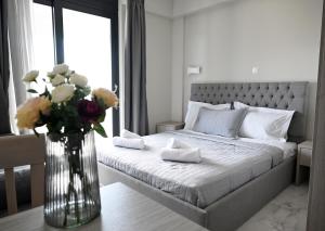 Un dormitorio con una cama con un jarrón de flores en ALTA MARE, en Nea Peramos