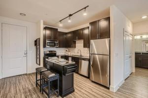 cocina con armarios marrones y nevera de acero inoxidable en Five Star Hotel-Style 2BD-Apartment at the Domain Shopping Center en Austin