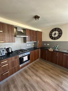 a kitchen with wooden cabinets and a clock on the wall at Down Town Pad*2Bed&Free Parking* in Glasgow