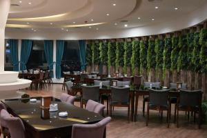 un restaurant avec des tables et des chaises et un mur de plantes dans l'établissement Khawarnaq Palace Hotel, à An Najaf