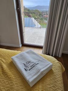 a white towel on a bed in front of a window at Quinta do Penedo Real in Viana do Castelo