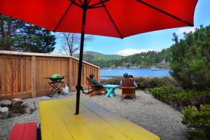 two people sitting on a bench under a red umbrella at John Henry's Marina and Resort in Garden Bay