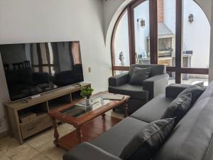 sala de estar con sofá, TV y mesa en Hermoso Departamento De Lujo, en Lima