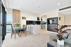 uma cozinha e sala de estar com uma mesa e uma televisão em Sensational Sun Sets in the Heart of the Viaduct em Auckland