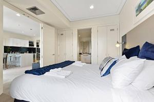 uma grande cama branca com almofadas azuis e brancas em Sensational Sun Sets in the Heart of the Viaduct em Auckland