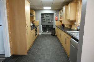 a large kitchen with wooden cabinets and a tile floor at Large 4 Bed House, Sleeps 7, Near NEC, BHX, City Centre in Birmingham