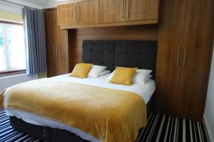 ein Schlafzimmer mit einem großen Bett mit gelben Kissen in der Unterkunft Large 4 Bed House, Sleeps 7, Near NEC, BHX, City Centre in Birmingham