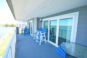 porche con sillas azules y mesa de cristal en Harbour Island 303L Condo, en Ocean City