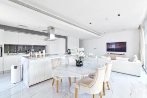 a white kitchen and dining room with a table and chairs at Premium 2+1 BR condo in the heart of Bluewaters Island in Dubai