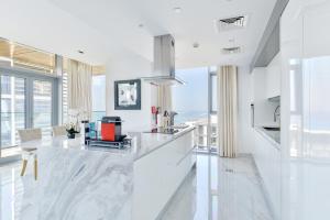 ドバイにあるPremium 2+1 BR condo in the heart of Bluewaters Islandのキッチン(白い大理石のカウンタートップ、大きな窓付)