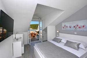 a white bedroom with a bed and a tv at Villa Stonehouse 2 in Milna