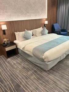 1 dormitorio con 1 cama grande y 1 silla azul en فندق غسن (الإسكان), en Medina