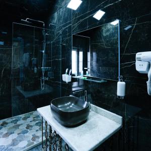 a black bathroom with a sink and a shower at Avrasya Hotel in Baku