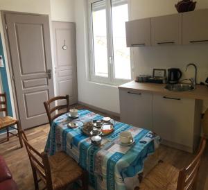 uma cozinha com uma mesa com uma toalha de mesa azul em Les chambres du Phare em Le Port-des-Barques
