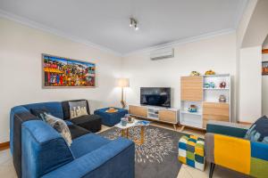 a living room with blue couches and a tv at Avenue Apartment Vilamoura in Quarteira