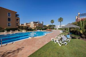 a swimming pool with two lawn chairs and a table at Avenue Apartment Vilamoura in Quarteira