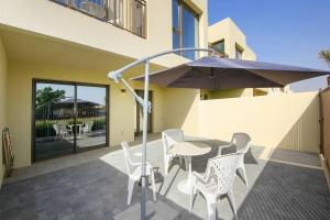 patio ze stołem, krzesłami i parasolem w obiekcie Green Haven 3BR Villa-Golfside Grandeur-Emmar South w Dubaju
