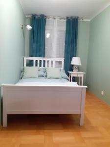 ein weißes Bett in einem Zimmer mit blauen Vorhängen in der Unterkunft GREEN AP Nalkowskich in Lublin