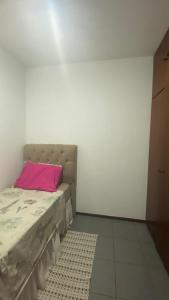 een slaapkamer met een bed met een roze kussen bij Quarto Privativo Zona Sul RP in Ribeirão Preto