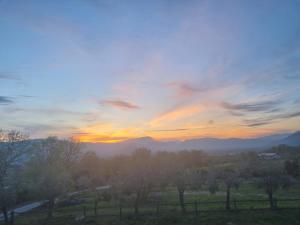 una puesta de sol sobre un campo con árboles y montañas en Masseria La Rocca, en Pacentro