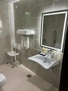 y baño con lavabo, espejo y aseo. en فندق غسن (الإسكان) en Medina