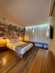 a bedroom with a large bed and a painting on the wall at JaguatiricaCoffee Hospitality in Monte Verde