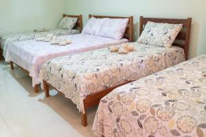 three beds in a room with pink and purple blankets at pousada Anna Assumpta in Severínia +16 photos