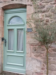 a green door on a stone building with a tree at Mine d'Ore Petit Gîte de la Chouette d'Or in Thoste +4 photos