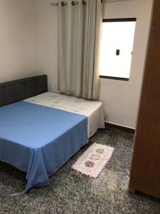 1 dormitorio con cama, ventana y alfombra en Casa Iriri, en Anchieta