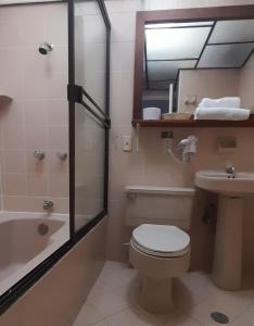 a bathroom with a toilet and a sink and a mirror at Hotel Laureles 70 in Medellín