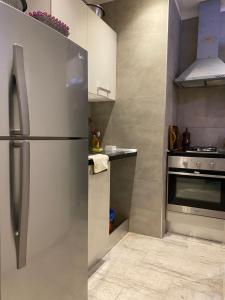 La cuisine est équipée d'un four et d'un réfrigérateur en acier inoxydable. dans l'établissement Coquette appartement sahloul 4, à Sousse