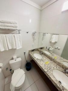 uma casa de banho com 2 lavatórios, um WC e um espelho. em Spazzio diRoma em Caldas Novas