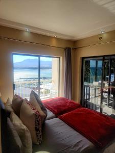 a bedroom with a large window with a view of the ocean at Bikini Beach Manor in Gordonʼs Bay +84 photos
