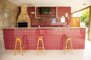 una cucina con un bancone piastrellato rosso con due sgabelli da bar di Apartamento Rio Das Ostras! 09 minutos Costa Azul a Rio das Ostras