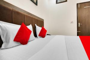 a bedroom with a bed with red and white pillows at Hotel O King Star Residency in Bathinda +25 photos