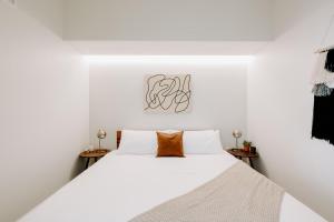 ein weißes Schlafzimmer mit einem großen Bett mit weißer Bettwäsche in der Unterkunft Estudio Tranquilo Modern Loft - Zuni Lofts in Denver