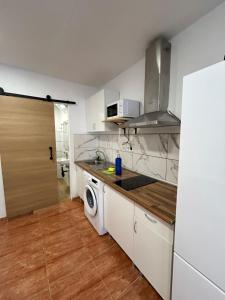 a kitchen with white cabinets and a washer and dryer at Maximum Beach in Arinaga