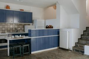 a kitchen with blue cabinets and a table and stool at The Sunset by KHI in Kithnos