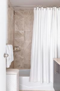 a bathroom with a white shower curtain and a tub at Luxury Private Apt New York City View in New York