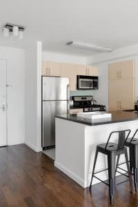 a kitchen with a stainless steel refrigerator and black chairs at Luxury Private Apt New York City View in New York