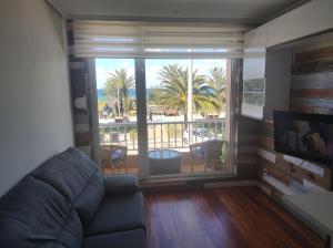 Una sala de estar con un sofá y una ventana grande. en APARTAMENTO EN LINEA DE PLAYA, en Suances