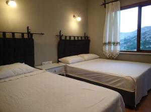 a bedroom with two beds and a window with mountains at TARiH OTEL NEMRUT DAGI in Karadut