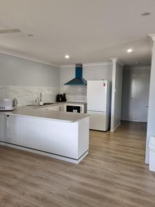a white kitchen with a sink and a refrigerator at Markwell St Villas in Kingaroy