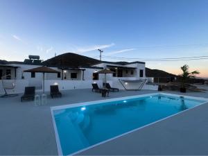 una piscina con sillas y sombrillas en un patio en O Mylos en Ermoupoli